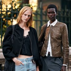 two women wearing a black jacket and a brown jacket with jeans