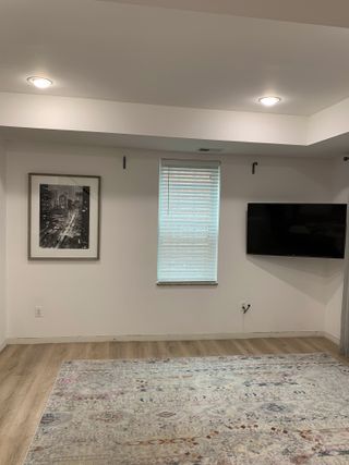 A living room with a bare wall and a TV mounted in the corner