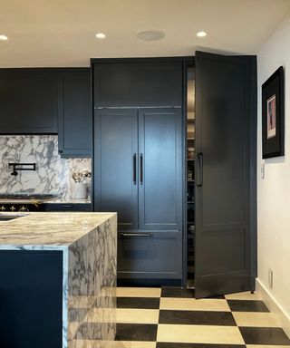 A black-and-white kitchen with checkered floors and a hidden pantry