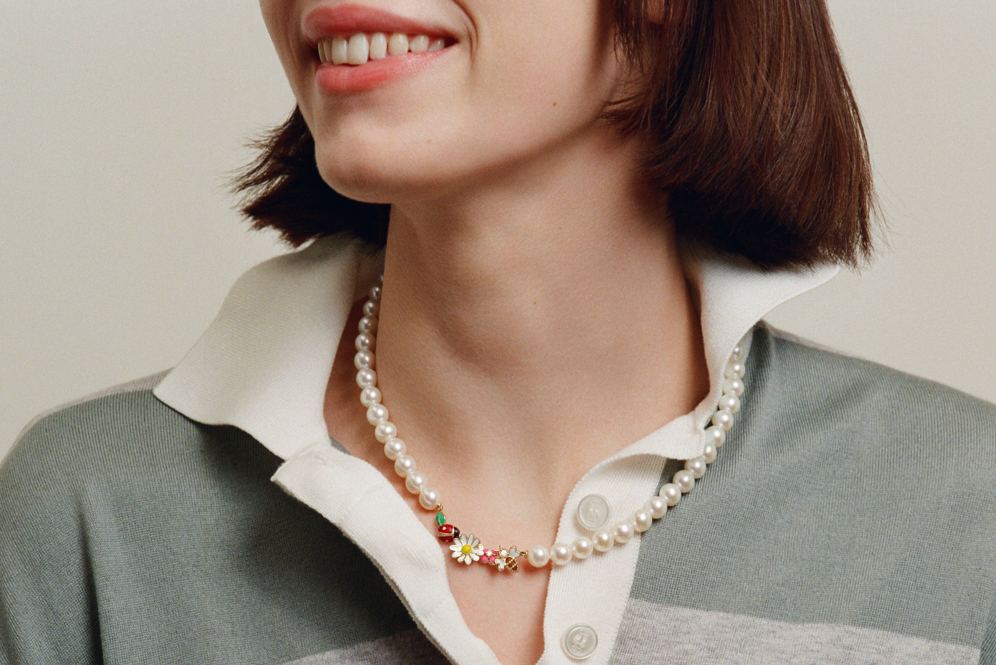 Model wearing a pearl necklace with ladybird and daisy charms
