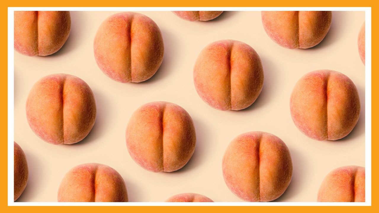 A detailed image of a freshly picked ripe peach. Photographed on a peach colored background.