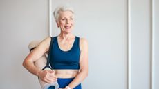 Woman with a rolled up mat secured with a strap slung over her right shoulder