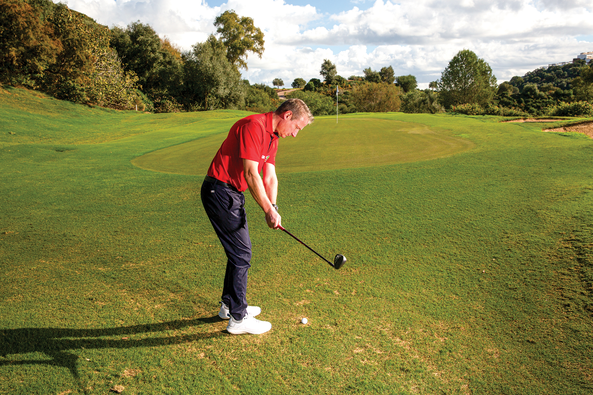 Anders Mankert in the backswing with a wedge, chipping from a tight lie around the green, demonstrating the correct technique that a high-handicapper should use for this short game shot
