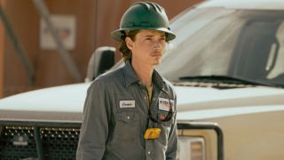 Jacob Lofland as Cooper Norris walking by a truck in a heard hat in Landman.