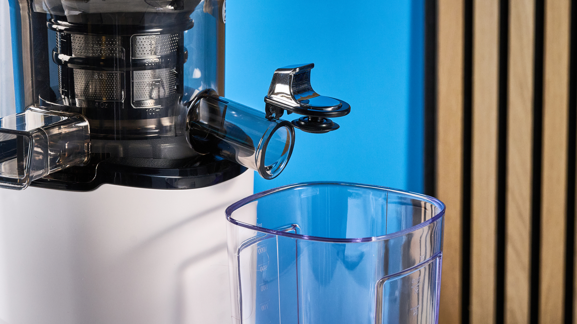Kuvings Auto8 hands-free slow juicer photographed on a blue background.