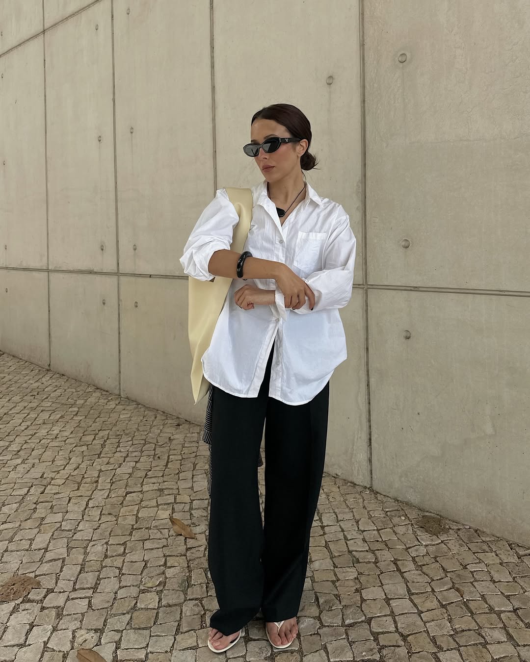 @deborabrosa wears a white linen shirt, black linen trousers and white leather flip-flops