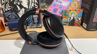 Sennheiser HD 505 open-back headphones on grey music streamer in front of busy bookshelf