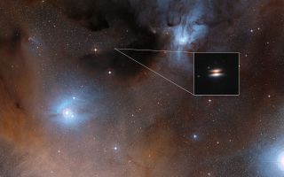The young star 2MASS J16281370-2431391 lies in the Rho Ophiuchi star formation region, about 400 light-years from Earth. It is surrounded by a protoplanetary disk of gas and dust that is seen nearly edge-on from Earth; the disk's appearance in visible-light images has led to its being nicknamed the Flying Saucer. The main image shows part of the Rho Ophiuchi region; an enlarged close-up infrared view of the Flying Saucer from the Hubble Space Telescope is shown as an insert.