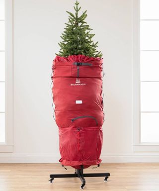 A slim upright rolling Christmas tree storage bag with faux tree enclosed and metal stand