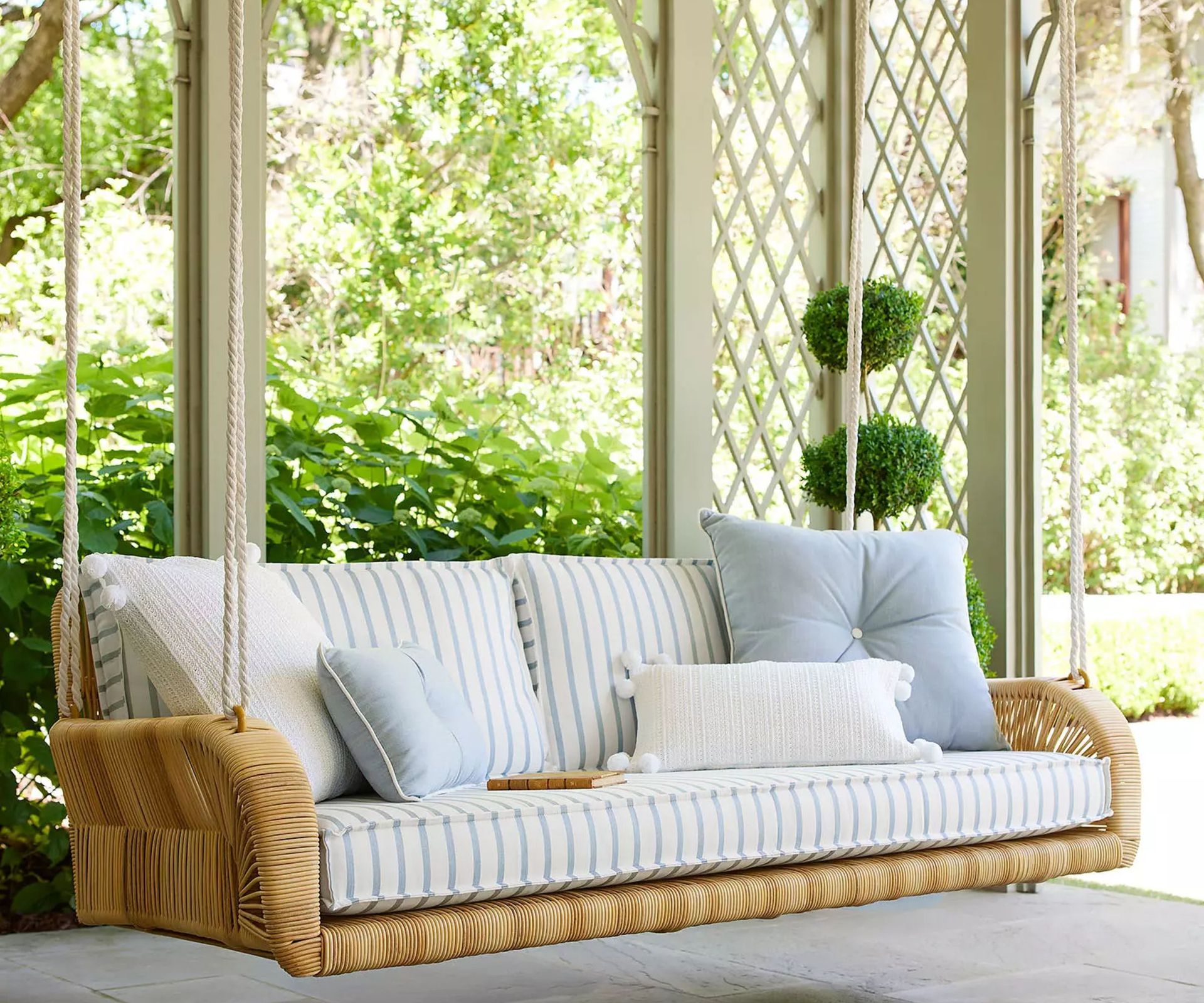 outdoor patio porch with a large wicker patio swing with striped cushions
