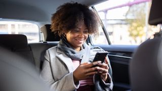 Woman sitting in the back of a car typing on phone, going through breadcrumbing in relationships