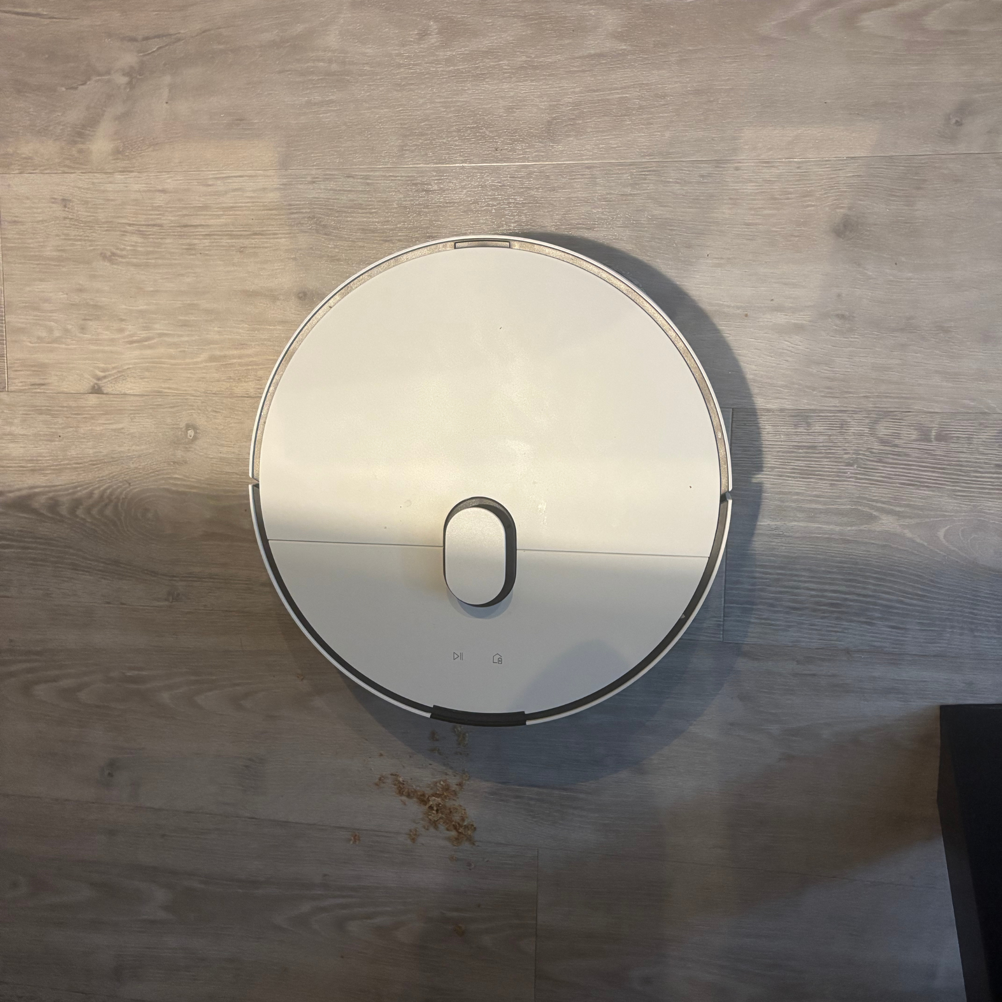Samsung robot vacuum positioned on hardwood floor besides food spilled on the floor