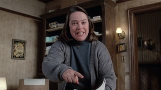 Kathy Bates as Annie Wilkes in Misery pointing a book pages