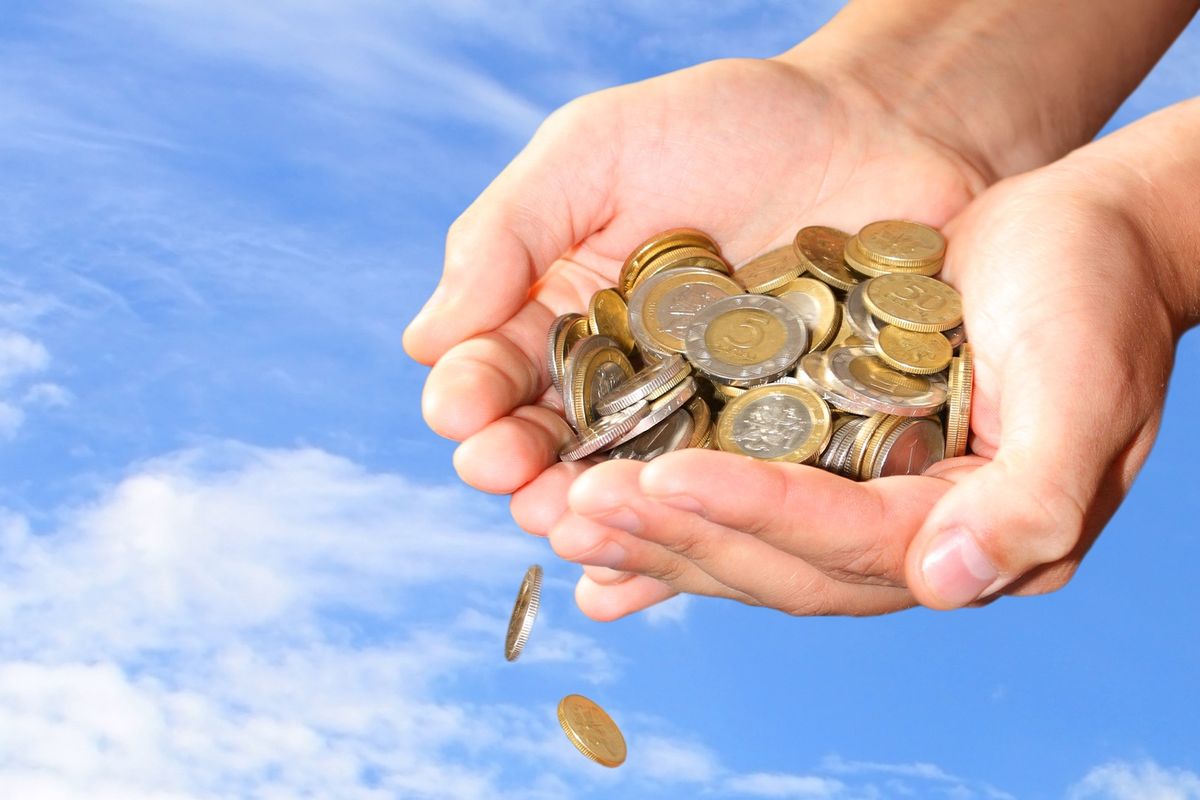 Hands holding coins with blue sky in background