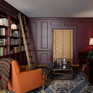 A library room with built-in bookshelves, a ladder and two sofas