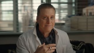 Alan Tudyk in Resident Alien holding a cigarette with his left hand. 