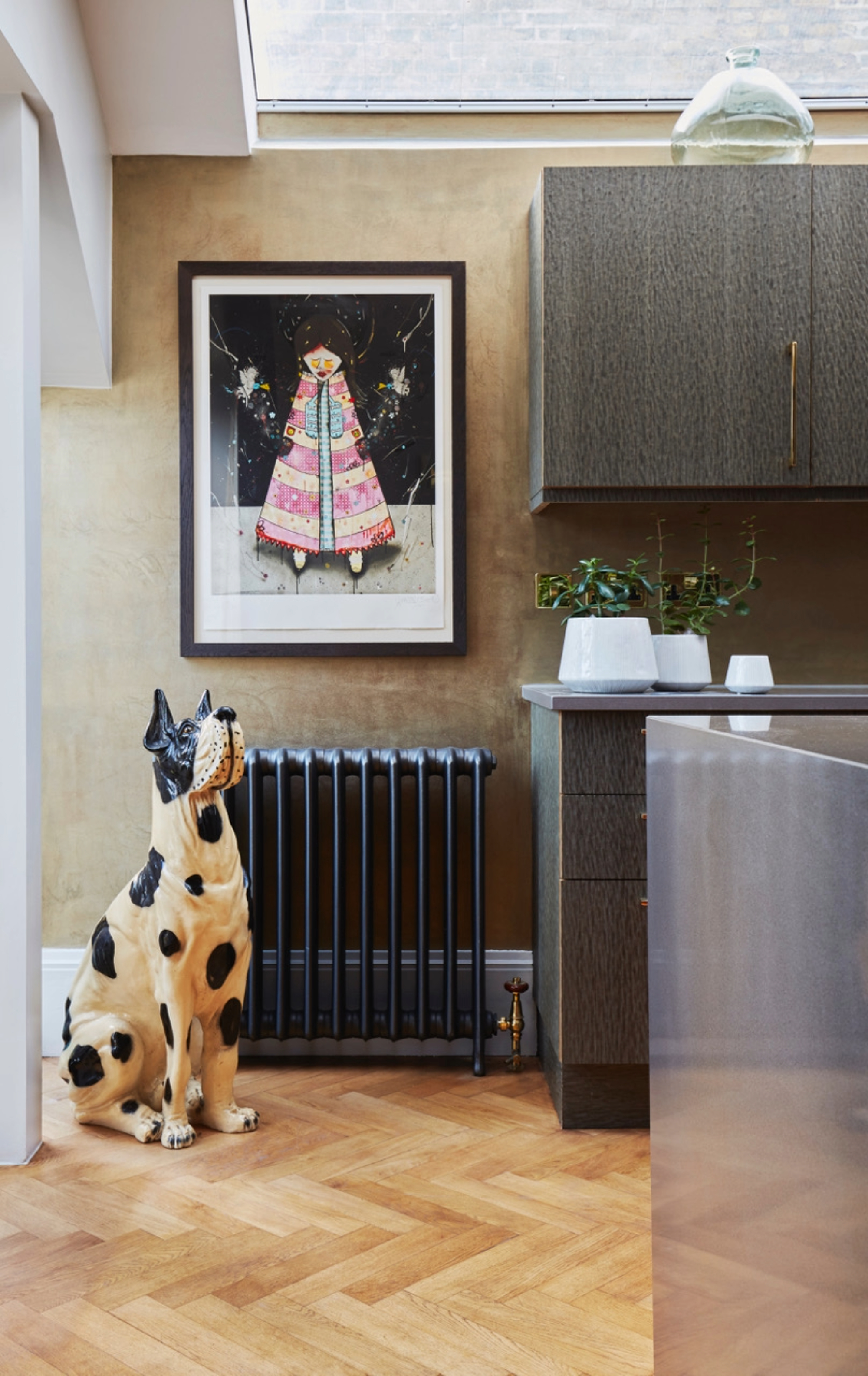 kitchen with dark timber cabinets, stainless island, parquetry floors, radiator, large dog sculpture, artwork on wall, and skulight overhead