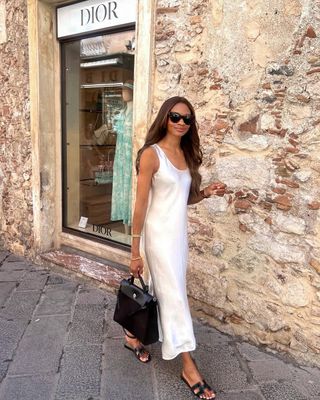 @symphonyofsilk wearing a white slip dress with sandals