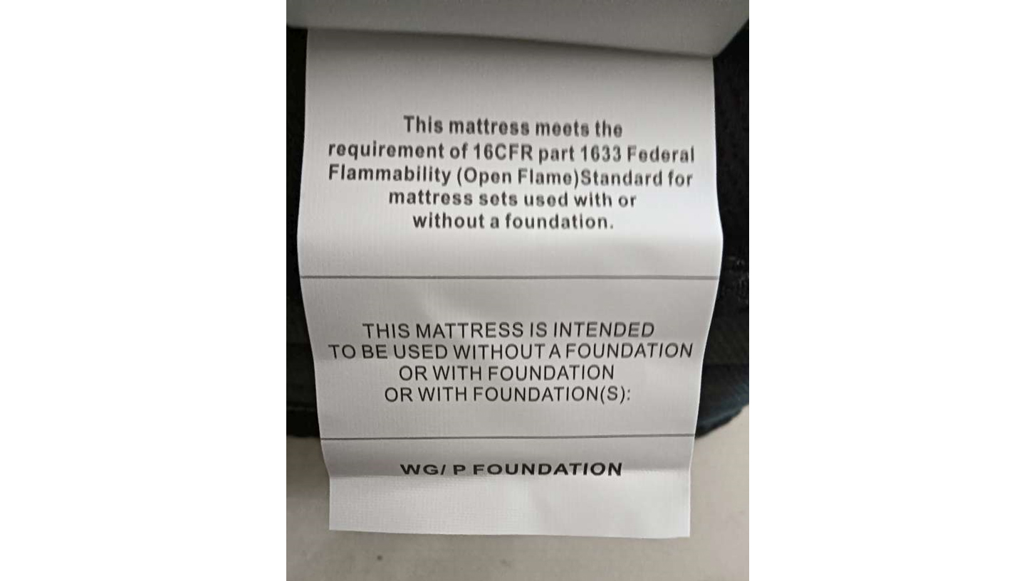A white information label on the side of a Crayan mattress. The label declares the mattress meets requirement 16CFR part 1633 Federal Flammability (Open Flame) Standard plus information about using the mattress with a foundation