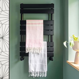 green bathroom with black radiator and towels