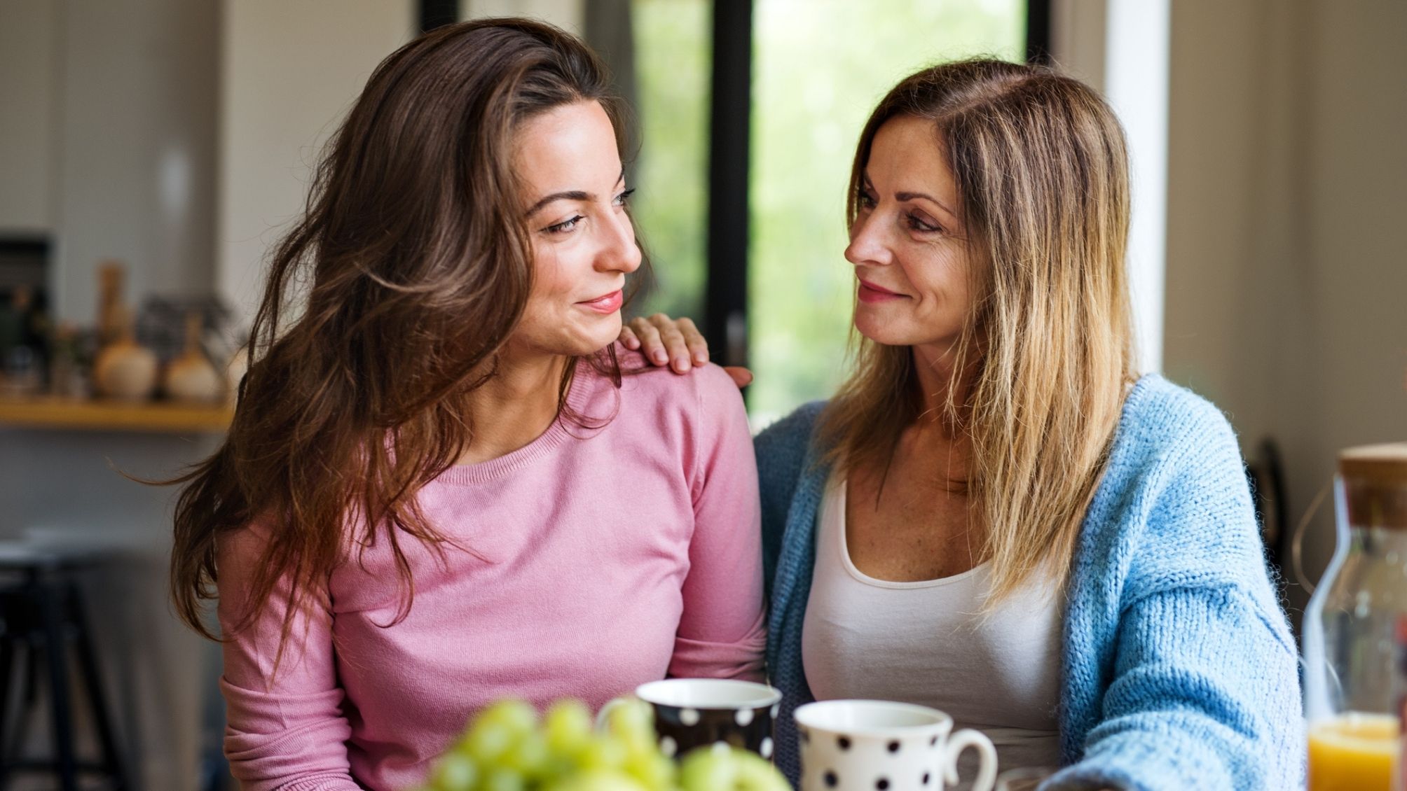 A mother and daughter talking and drinking coffee.