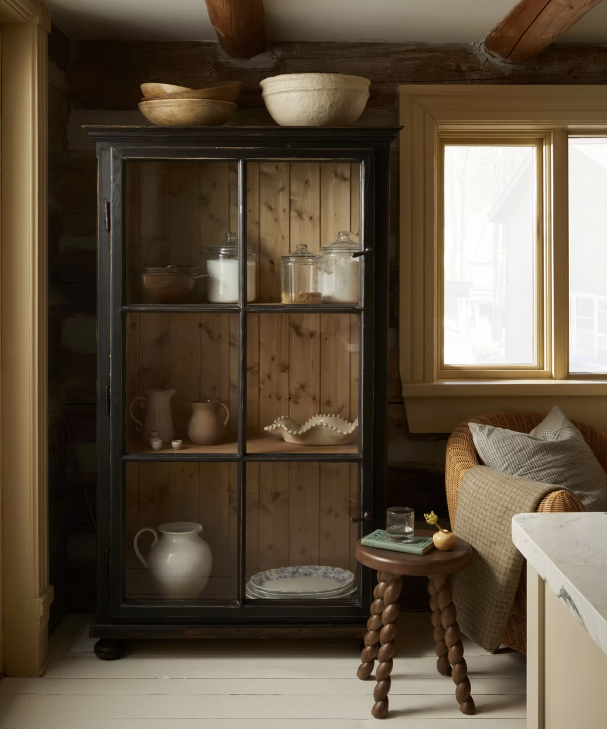 cabinet in the corner of a living room with jugs and jars on display in it