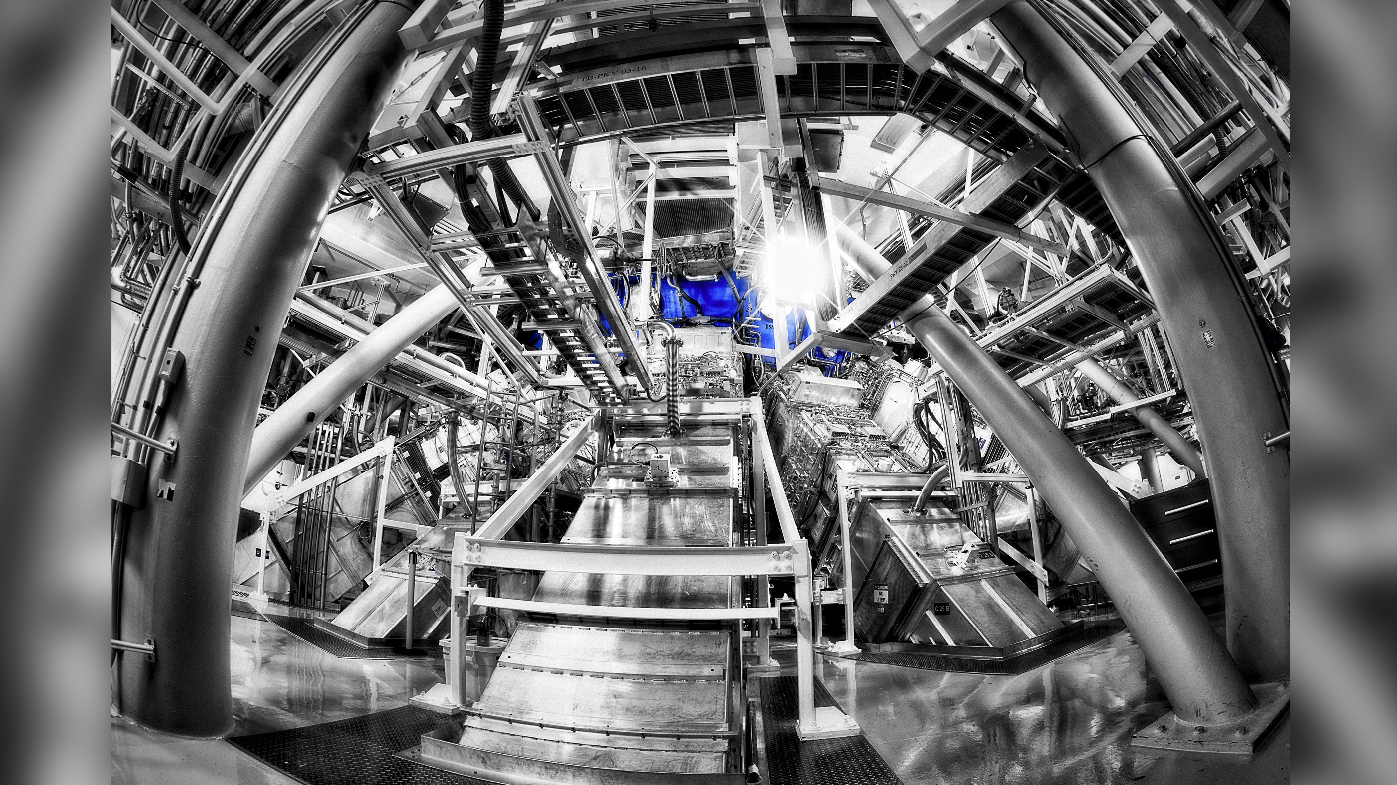 Damien Jemison, photographer at the National Ignition Facility (NIF), captured this image of the NIF laser beam lines entering a part of the target chamber. Jemison needed five exposures to capture the range of light in the dimly lit spot. He also converted the resulting image to monotone, saying "The end result is my artistic view of how I feel when standing face-to-face with the highest-energy laser in the world."