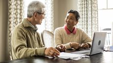 An older couple sit in front of a laptop talking