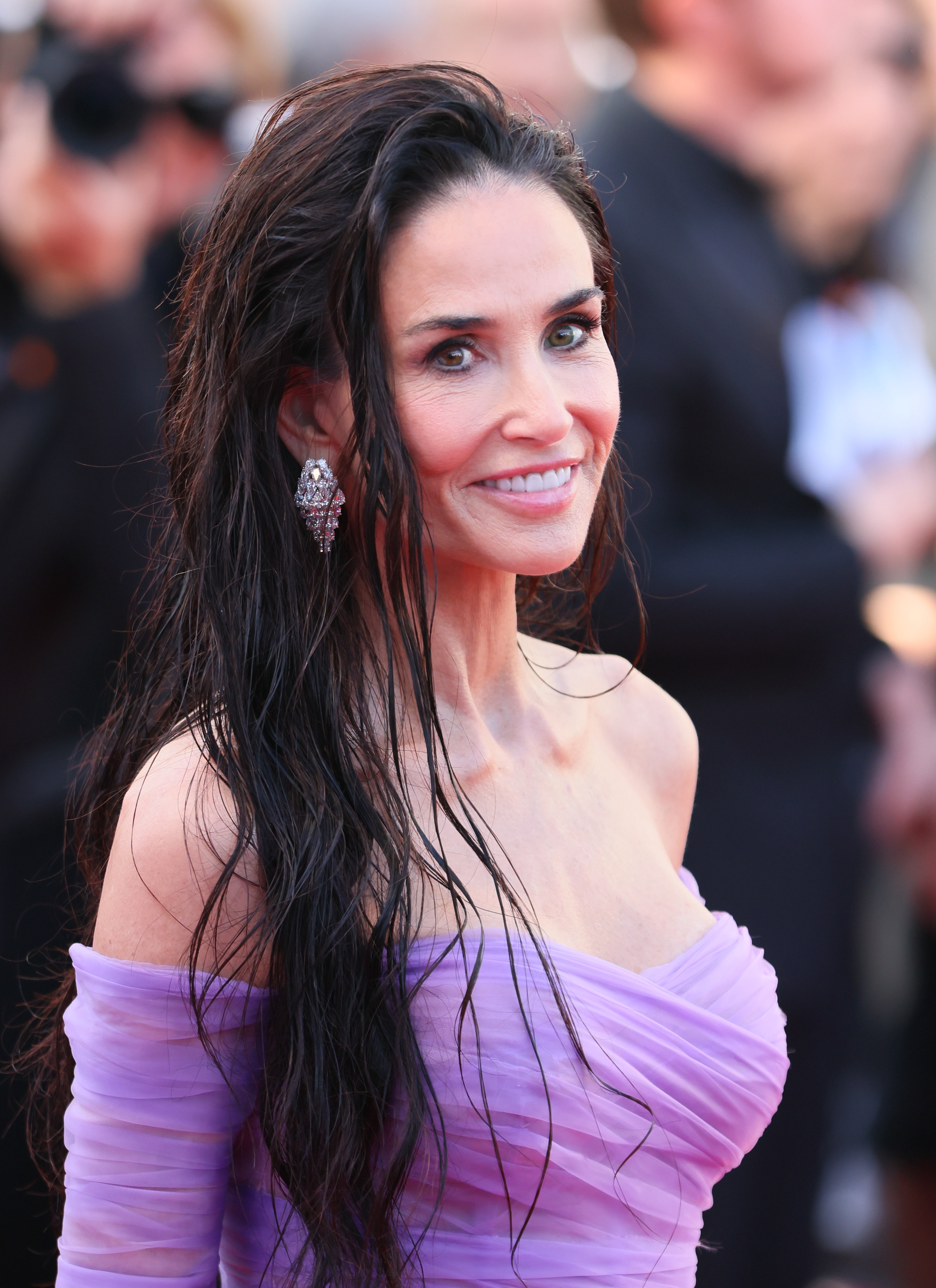 a white woman poses on a red carpet wearing a lavender gown and wavy hair