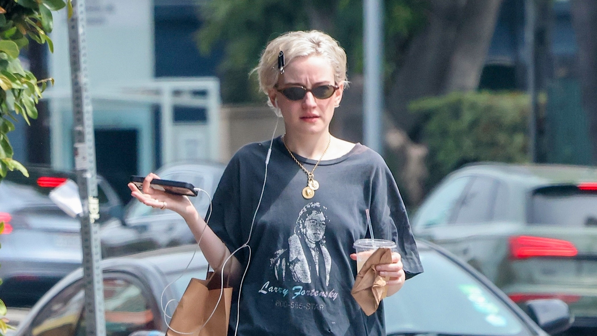 Julia Garner wearing a navy graphic tee, green barrel pants, and Puma ballet flats.