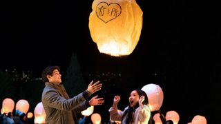 A boy and girl release a Chinese lantern into the night sky.