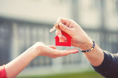 Close up shot of hands of an estate agent handing keys to a buyer