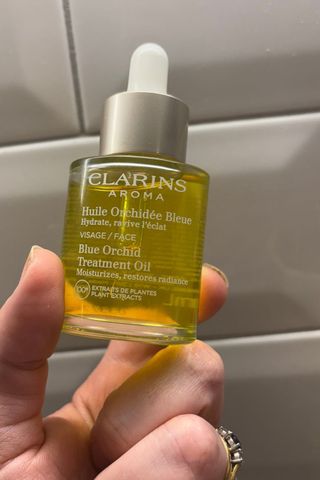 A PICTURE OF CLARINS BLUE ORCHID FACE OIL BEING HELD