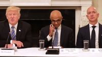 Satya Nadella sits between Donald Trump and Jeff Bezos looking awkward