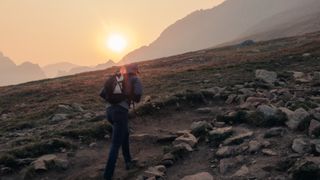 A hiker walks up Mount Bierstadt under a low sun in Colorado