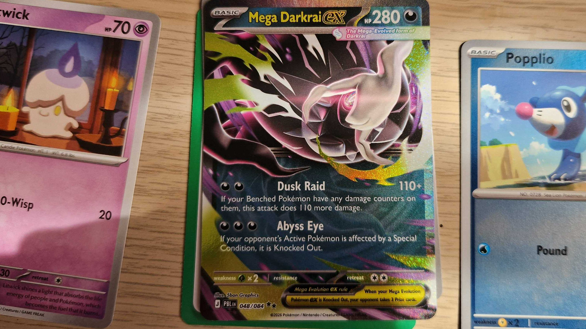 A trio of Pokemon cards on a wooden surface