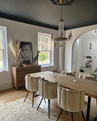 A dining room with cream chairs and charcoal gray ceiling