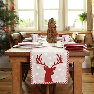 Christmas table with red reindeer on runner, red and white tableware