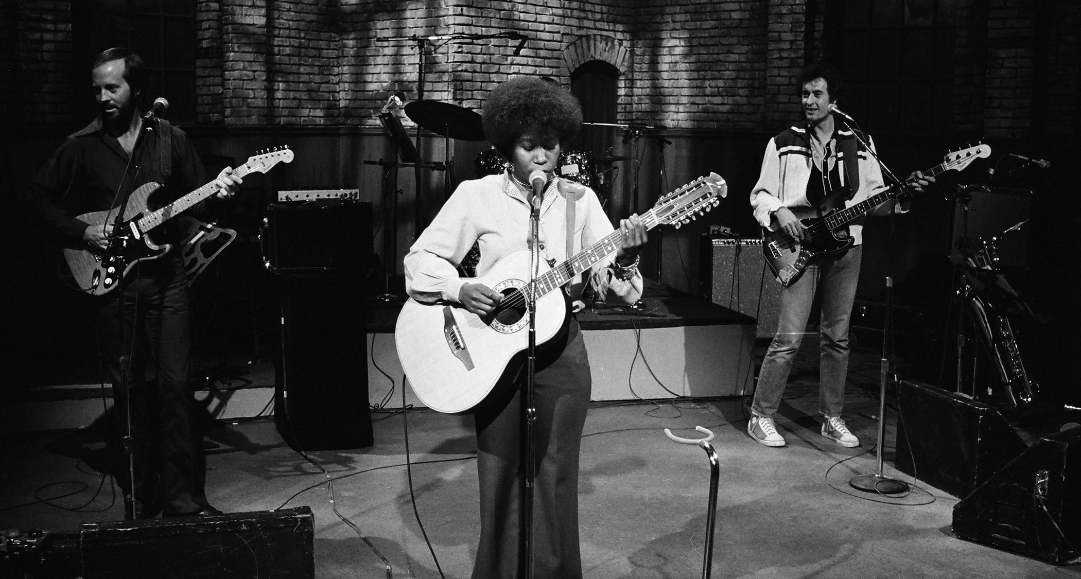 A black-and-white still of Joan Armatrading performing live on SNL in 1977.