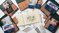 selection of pastel pencils and a sketchpad in the middle