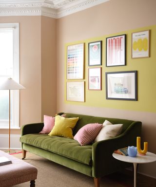 living room with pale pink walls, dark green sofa and yellow gallery wall