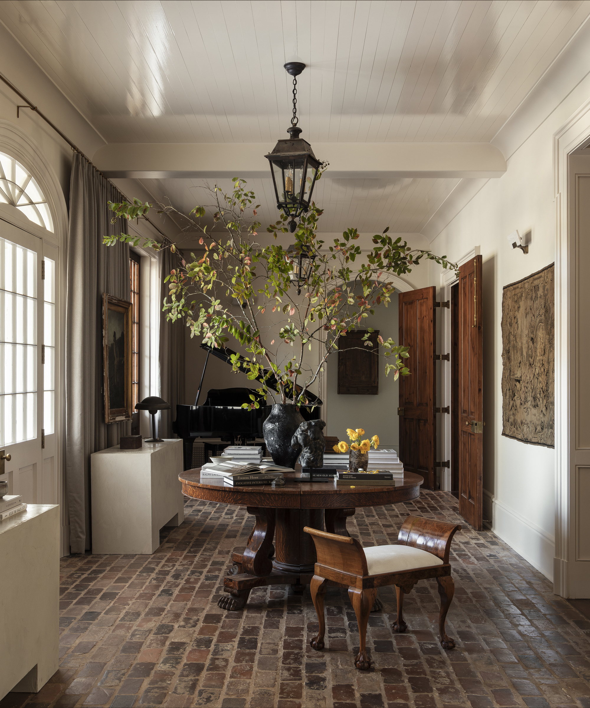 entryway with brick flooring and round wood table covered in books