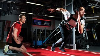 Man does sled pull with a harness in a gym