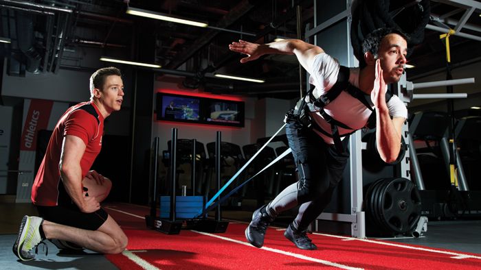 Man does sled pull with a harness in a gym