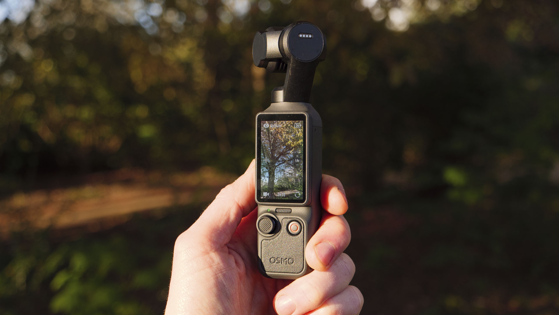 DJI Osmo Pocket 4 vlogging camera in the hand with natural background at golden hour