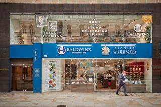 A man walking past a Stanley Gibbons shopfront