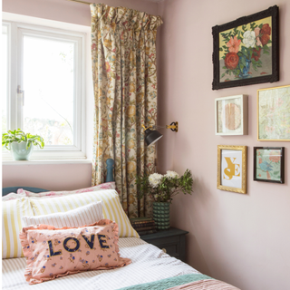 a pink painted bedroom with colourful bedding and patterned bedroom curtains over window