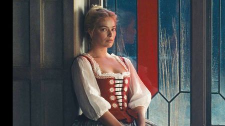 Margot Robbie's Catherine sitting on a window seat at night in 2026's Wuthering Heights movie