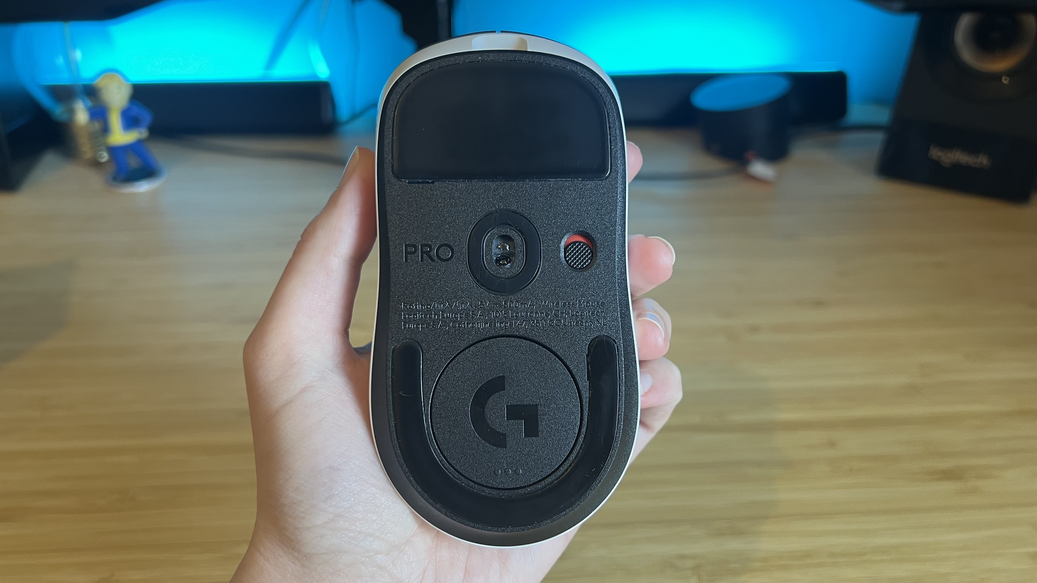 Hand holding Logitech G Pro X2 Superstrike gaming mouse with sensor and connection button facing the camera