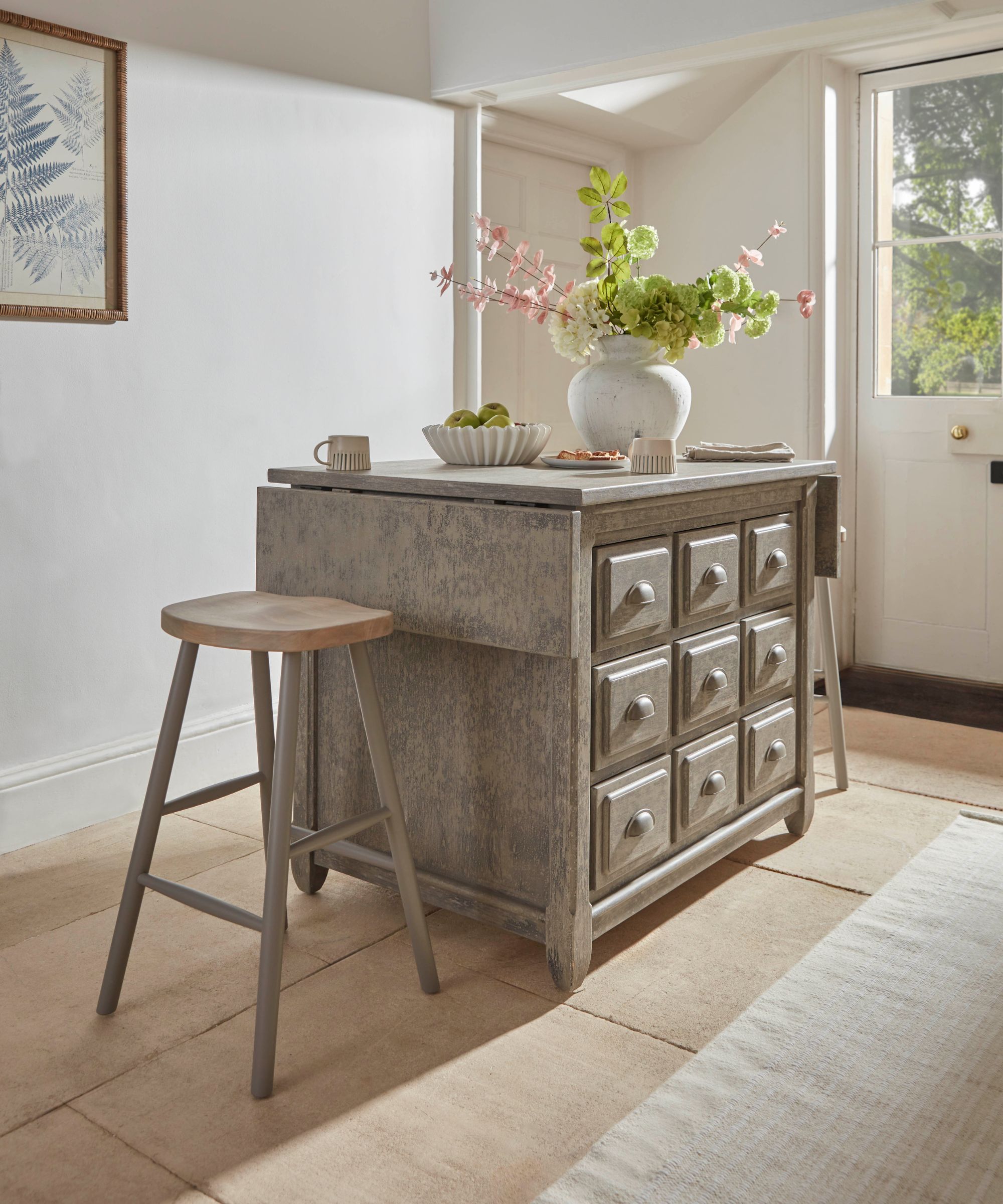 A rustic freestanding kitchen island with multiple drawers, a weathered wood finish and stool seating, styled as a practical prep and dining spot.